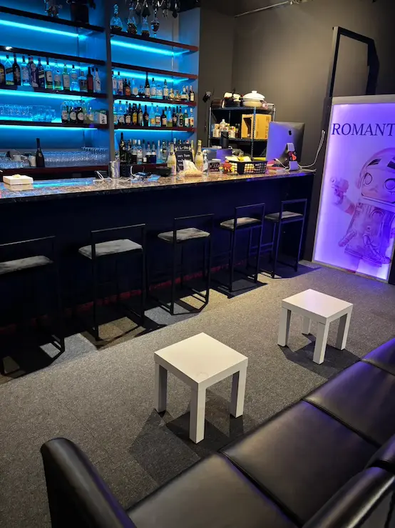 The bar counter inside EVE in Osaka, with backlit shelves, stools, and lounge seating