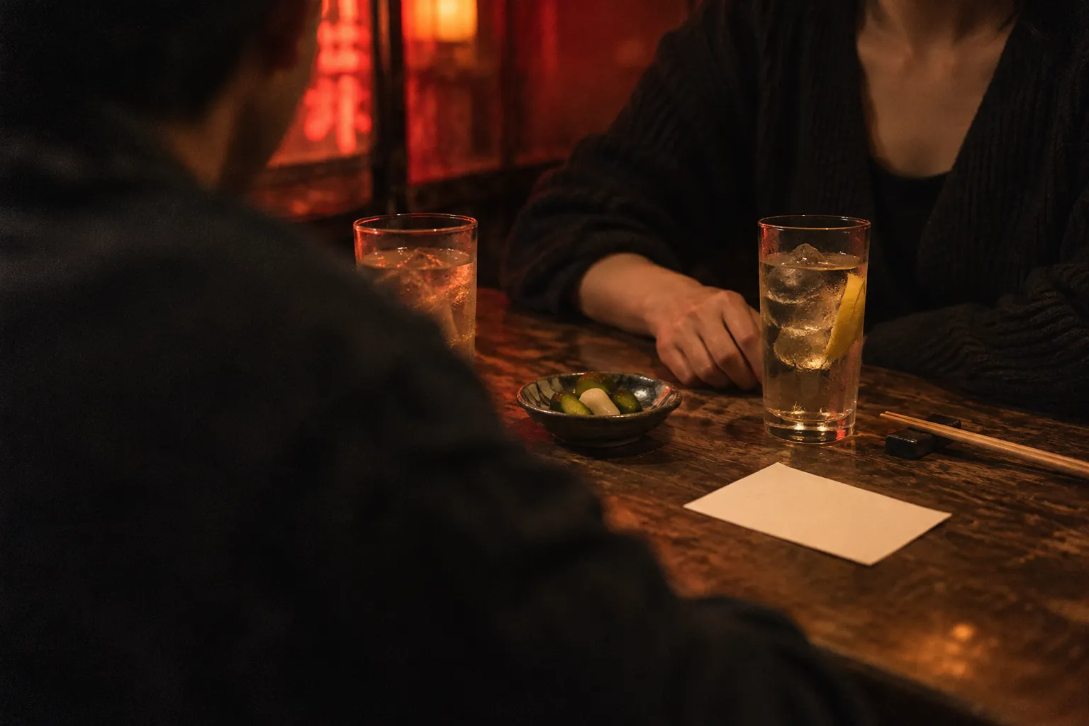 Two people seated at an izakaya table with a nomihodai plan card and drinks between them