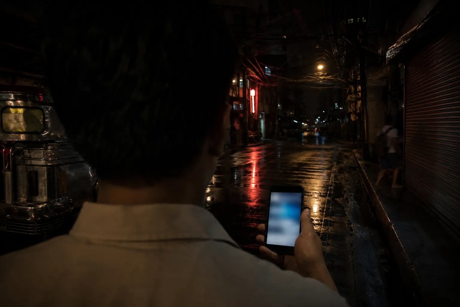 Philippines dating apps open on a phone in a hand on a wet Manila side street at night